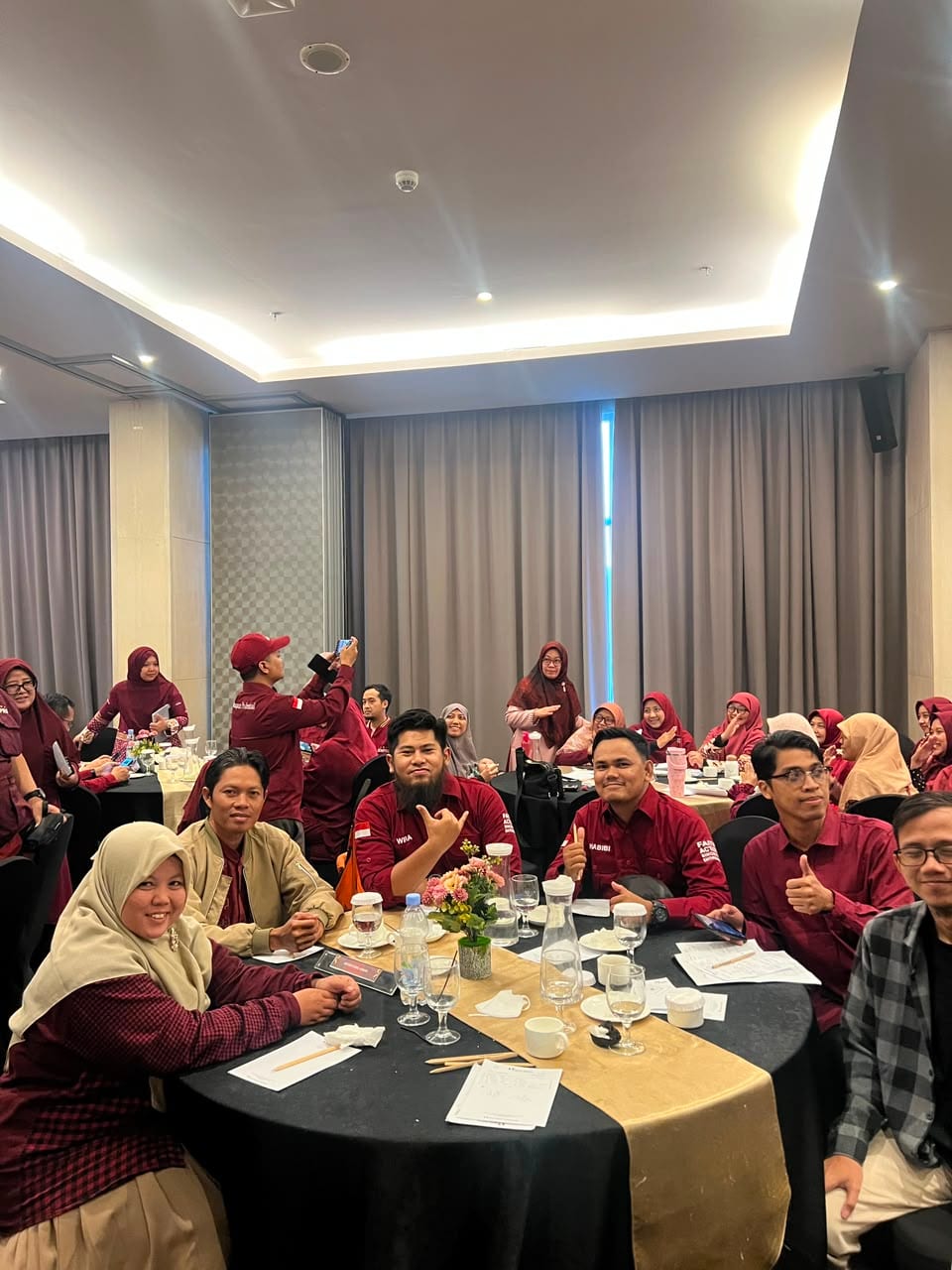 Wira seated at a round table among people in a red dress code at a Genpro Youth Entrepreneur event